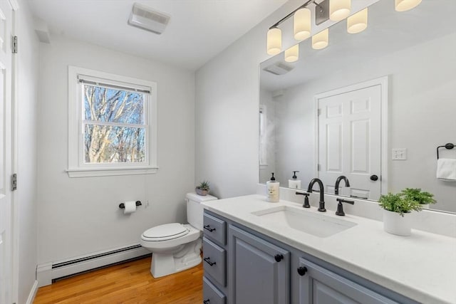 bathroom with wood-type flooring, toilet, vanity, and a baseboard heating unit