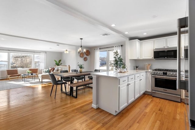 kitchen featuring beamed ceiling, white cabinetry, kitchen peninsula, stainless steel appliances, and light hardwood / wood-style flooring