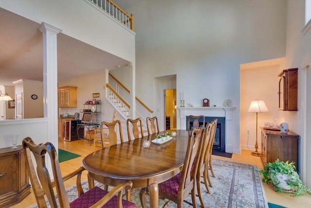 dining space featuring stairs, a high ceiling, light wood-type flooring, and ornamental molding