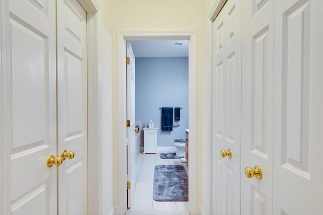 hall featuring light tile patterned floors and baseboards