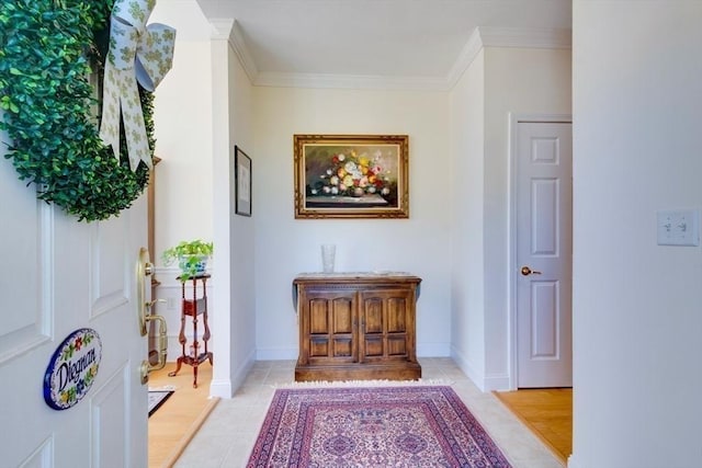 hall featuring light tile patterned floors, baseboards, and ornamental molding