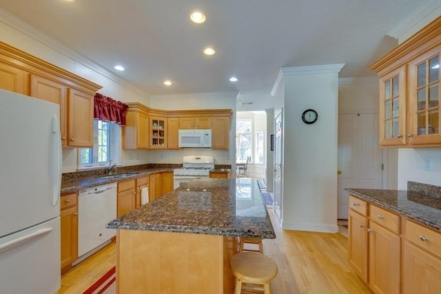 kitchen featuring a sink, white appliances, light wood-style flooring, and a center island