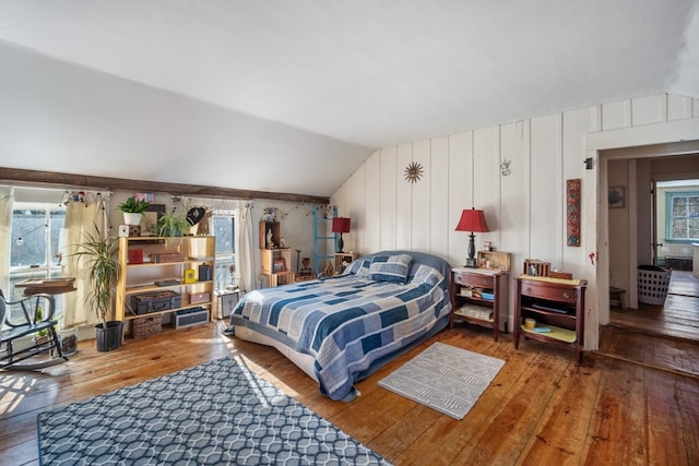 bedroom featuring wood-type flooring, wooden walls, and lofted ceiling