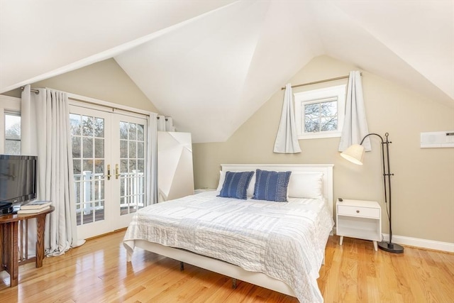 bedroom with hardwood / wood-style flooring, vaulted ceiling, and multiple windows