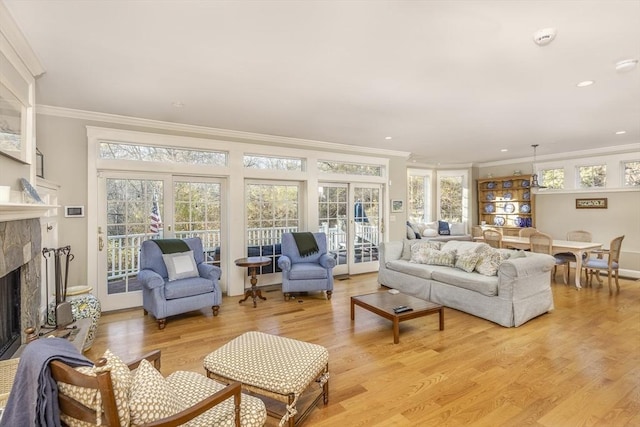 living room with a wealth of natural light, a fireplace, light hardwood / wood-style floors, and ornamental molding