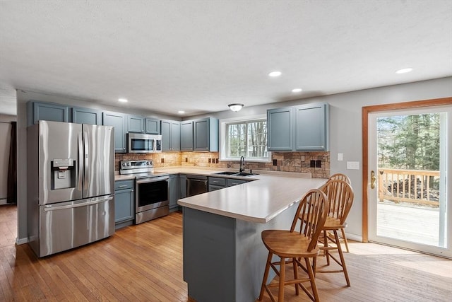 kitchen featuring a breakfast bar area, stainless steel appliances, a peninsula, and decorative backsplash