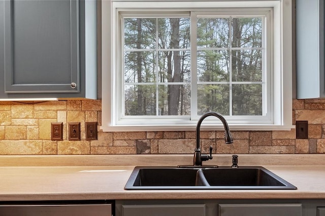 kitchen with a sink, backsplash, and light countertops