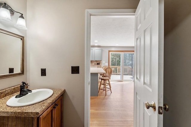 bathroom with recessed lighting, wood finished floors, and vanity