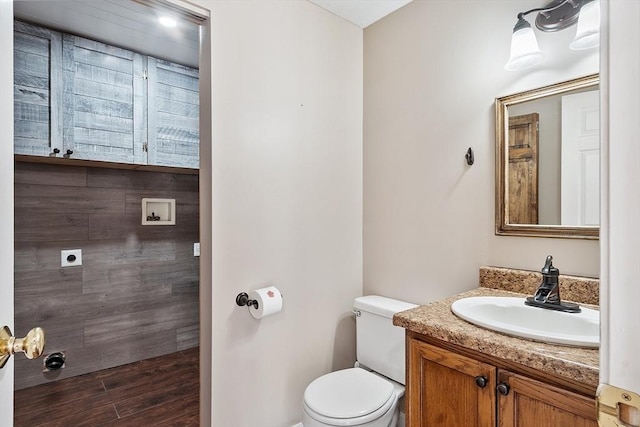 bathroom featuring toilet, wood finished floors, and vanity
