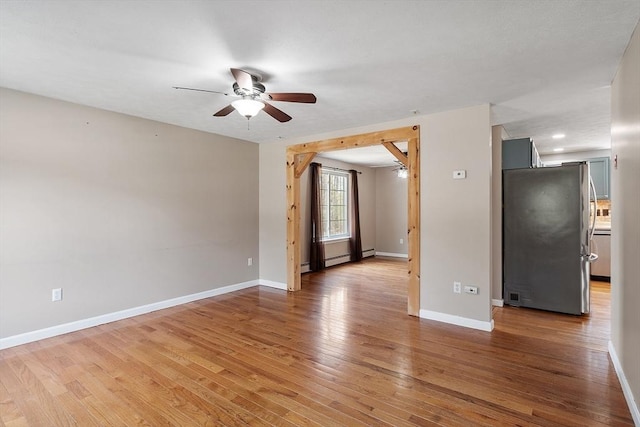 spare room with baseboards, ceiling fan, and light wood-style floors
