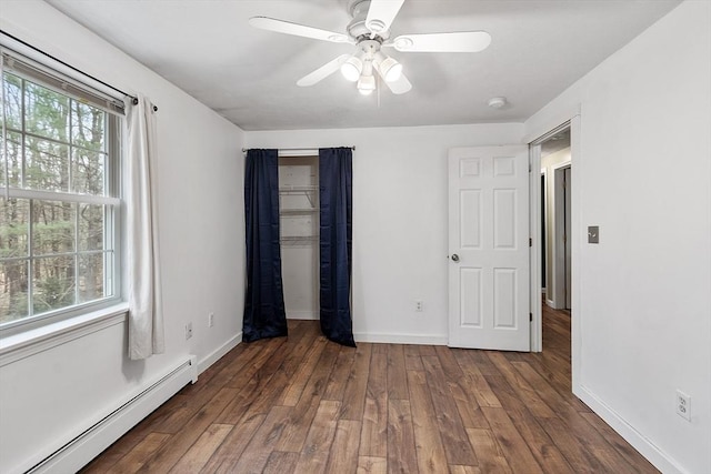 unfurnished bedroom featuring ceiling fan, hardwood / wood-style floors, a baseboard heating unit, baseboards, and a closet