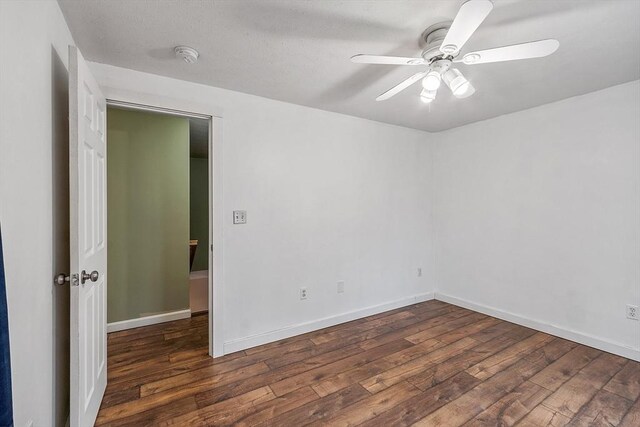 spare room featuring wood finished floors, a ceiling fan, and baseboards