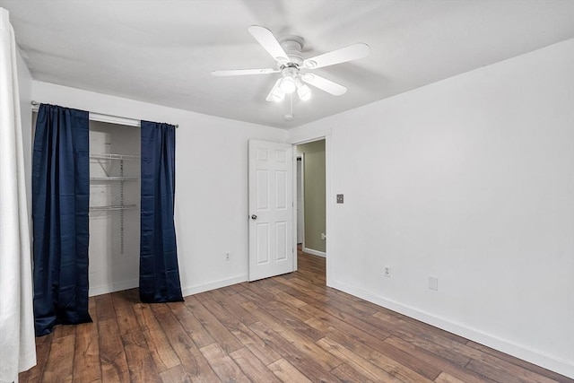 unfurnished bedroom featuring hardwood / wood-style floors, baseboards, ceiling fan, and a closet