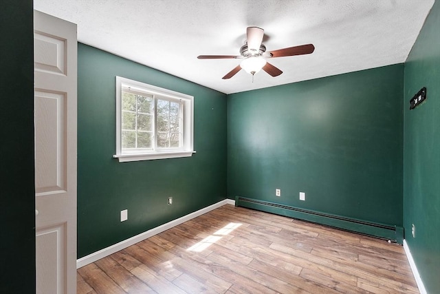 unfurnished room with wood finished floors, ceiling fan, baseboard heating, and baseboards