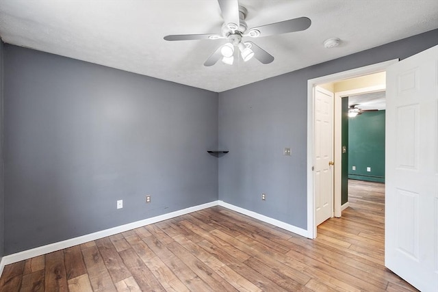 spare room with baseboards, baseboard heating, a ceiling fan, and wood-type flooring