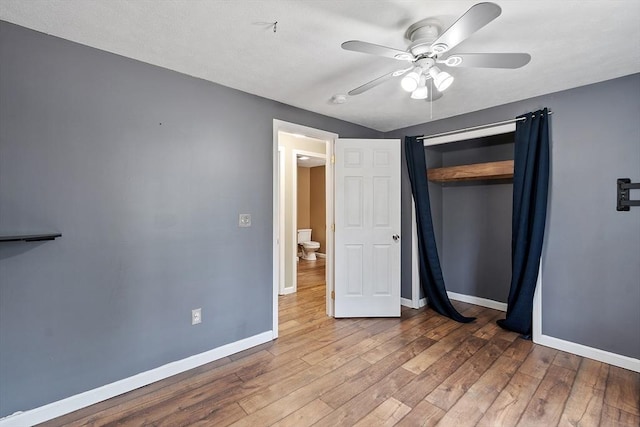 unfurnished bedroom with wood finished floors, a closet, a ceiling fan, and baseboards