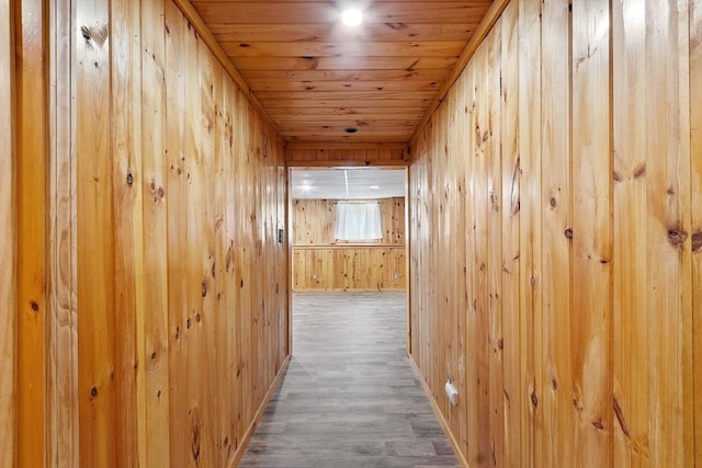 hall with wood walls, wood finished floors, baseboards, and wood ceiling