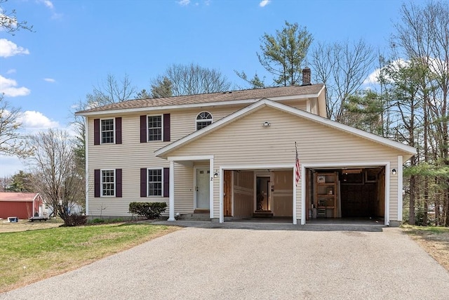 view of front of home with a front yard, a chimney, aphalt driveway, and a garage