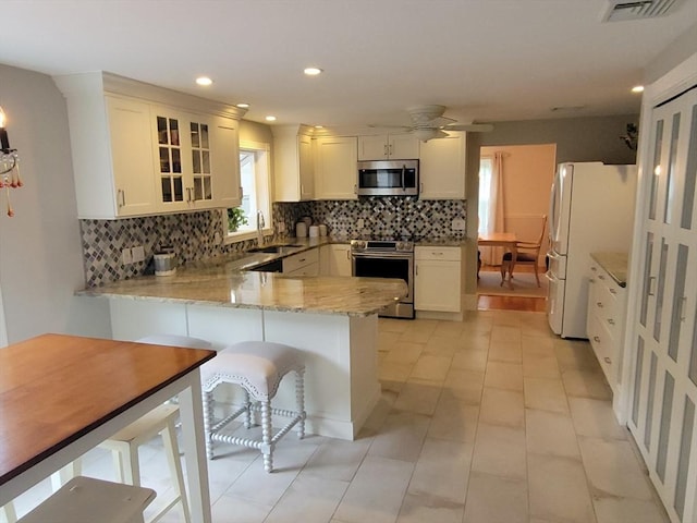 30 Ridgewood Ln, Quincy, MA 02169 - kitchen with stainless steel appliances, a peninsula, tasteful backsplash, light stone countertops, and glass insert cabinets