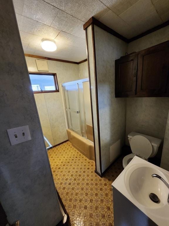 bathroom featuring toilet, ornamental molding, and sink