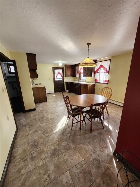 dining space with a textured ceiling, a baseboard radiator, plenty of natural light, and sink