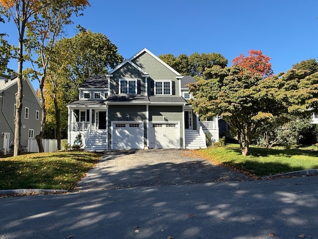 view of front facade with a front lawn, covered porch, and a garage