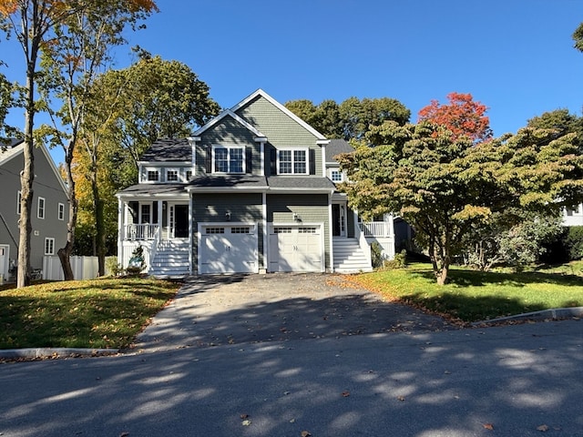 view of front facade featuring a front lawn, covered porch, and a garage