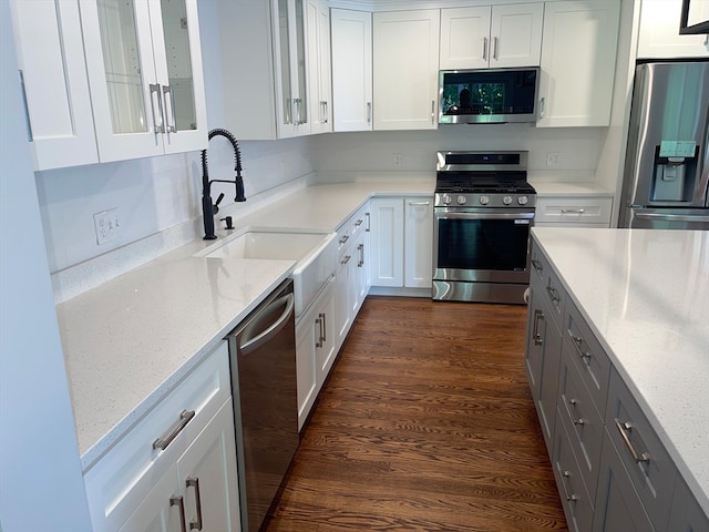 kitchen featuring dark wood-type flooring, white cabinets, sink, light stone countertops, and stainless steel appliances