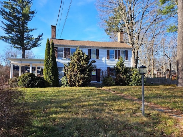 colonial house featuring a chimney and a front lawn