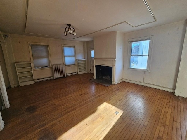 unfurnished living room with a chandelier, baseboard heating, wood-type flooring, and a fireplace with flush hearth