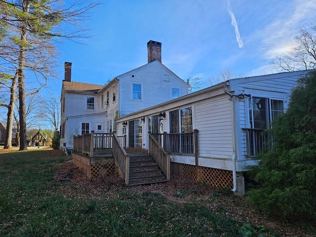 back of property with a chimney, a yard, and a deck