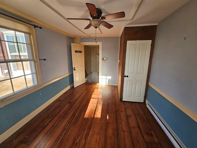 unfurnished bedroom with dark wood-style floors, baseboard heating, and baseboards