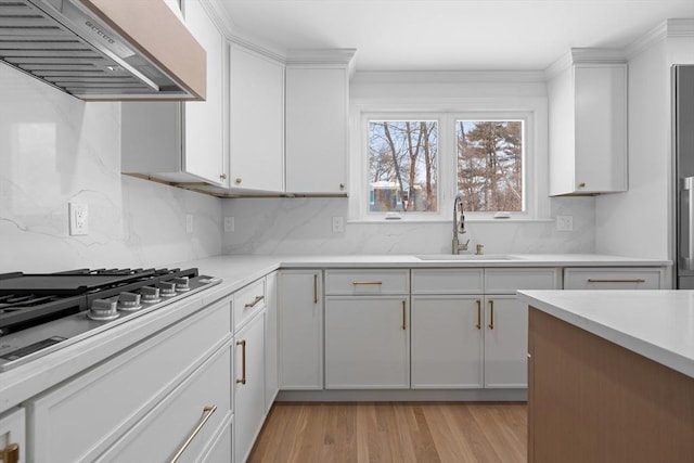 kitchen featuring white cabinetry, stainless steel gas stovetop, sink, and custom exhaust hood