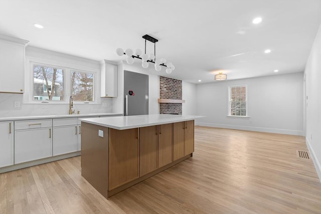 kitchen with sink, decorative light fixtures, white cabinets, and a kitchen island