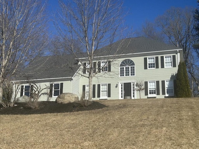 colonial-style house featuring a front yard