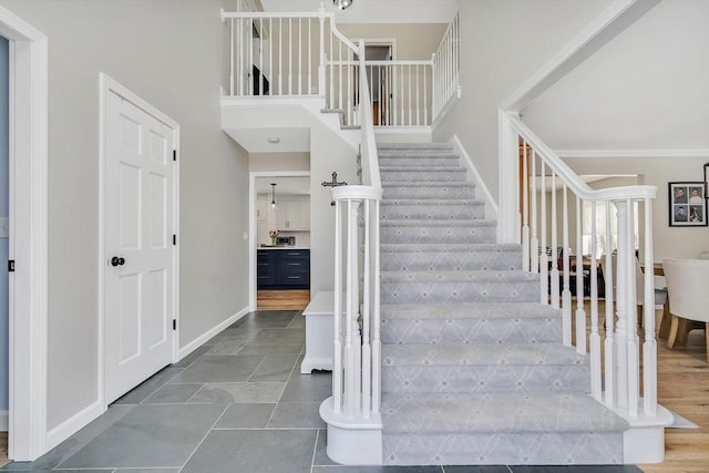 staircase with a high ceiling and baseboards