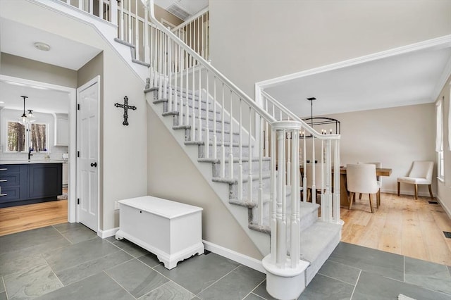 stairway with a chandelier, a high ceiling, wood finished floors, and baseboards