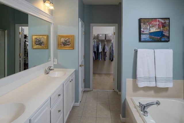 bathroom with tile patterned floors, a sink, a spacious closet, a bath, and double vanity