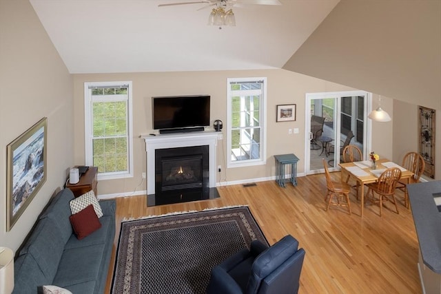 living area with vaulted ceiling, a healthy amount of sunlight, and wood finished floors