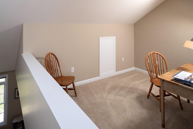 home office with vaulted ceiling, baseboards, and light colored carpet