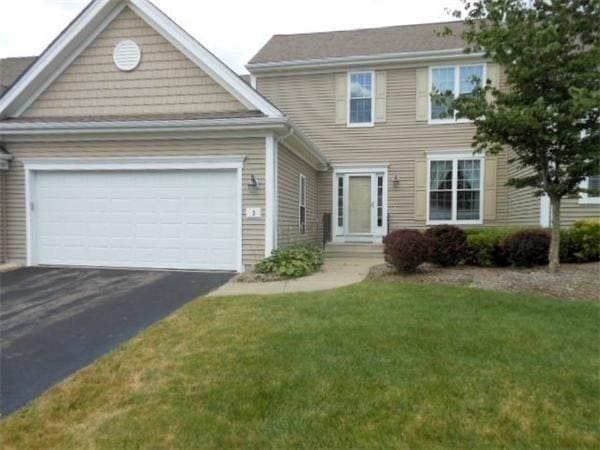 view of front of home featuring aphalt driveway, a front yard, and a garage
