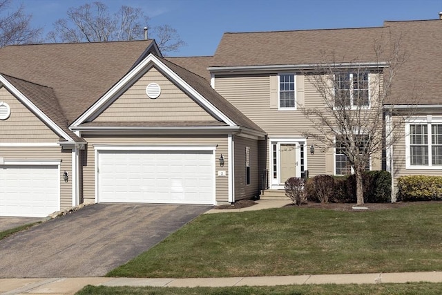 view of front facade with an attached garage, driveway, a shingled roof, and a front lawn