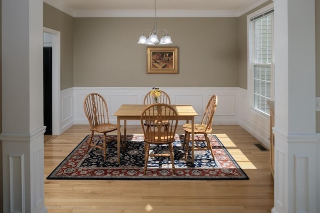 dining space with ornamental molding, a wainscoted wall, wood finished floors, and plenty of natural light
