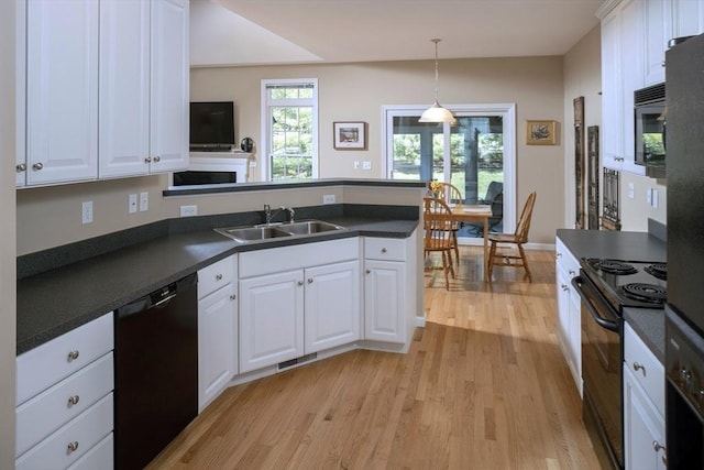 kitchen with dark countertops, a sink, light wood-style floors, black appliances, and a peninsula