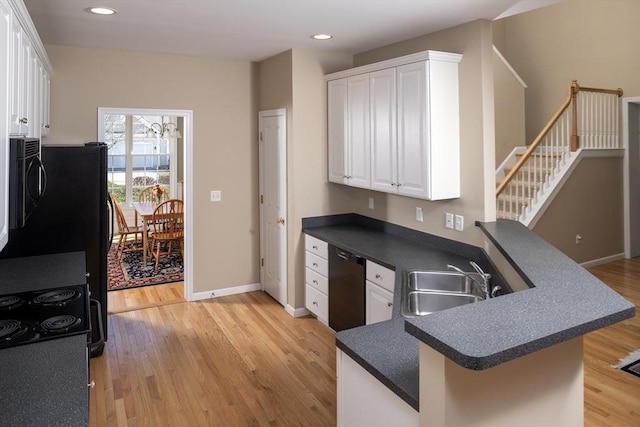 kitchen featuring light wood-style flooring, a sink, dark countertops, white cabinetry, and dishwasher