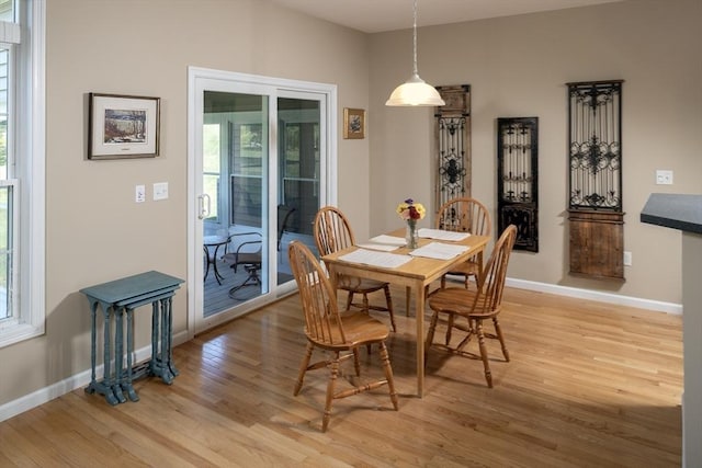 dining space featuring light wood finished floors, plenty of natural light, and baseboards