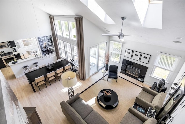 23 Matt Hoxie Trl Unit 23, Plymouth, MA 02360 - living room featuring high vaulted ceiling, wood finished floors, a glass covered fireplace, a skylight, and ceiling fan