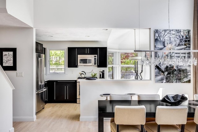23 Matt Hoxie Trl Unit 23, Plymouth, MA 02360 - kitchen with stainless steel appliances, dark cabinets, light wood-style floors, light countertops, and a kitchen breakfast bar