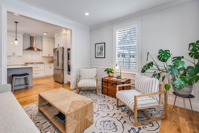 sitting room with crown molding and light hardwood / wood-style floors