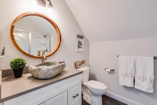 bathroom with hardwood / wood-style floors, vanity, vaulted ceiling, a shower with shower door, and toilet